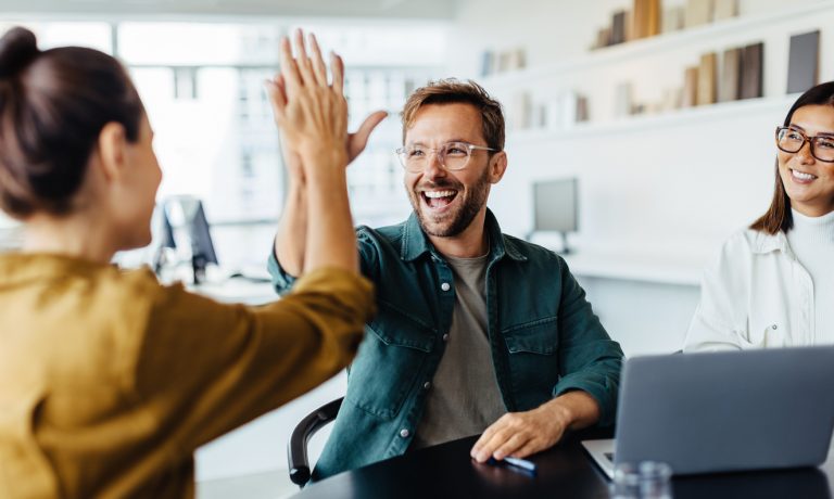 Successful business people giving each other a high five in a meeting